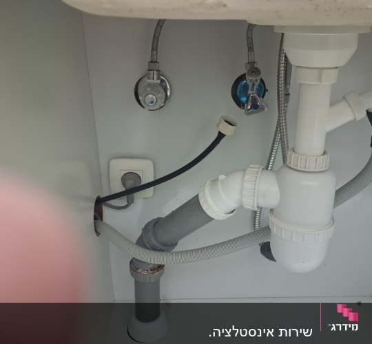 צנרת מתחת לכיור עם חיבורים וצינורות